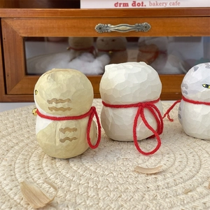 Close-up of cute wooden cat figurines with red strings and bells on a white mat