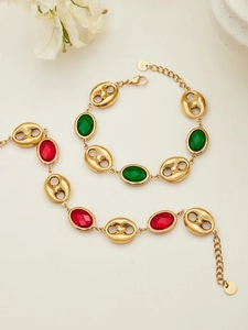 Detalle de pulseras de acero inoxidable dorado con piedras de vidrio ovales rojas