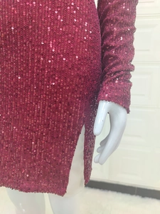 Gros plan sur le tissu à paillettes bordeaux et la fente latérale de la robe longue
