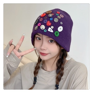 Close-up of purple knit beanie with colorful button accents on a female model