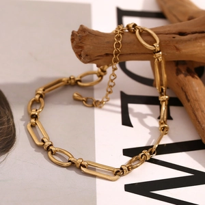 Detail of 14K gold plated stainless steel paperclip chain with water drop charm on wood