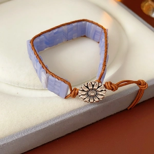 Dettaglio del bracciale in pelle intrecciata con pietre azzurre e fibbia a fiore d'argento