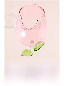 Detailed view of pink tulip glass with wavy rim and green leaf accents on stem