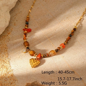 Detail of bohemian gold heart pendant necklace with natural tiger eye and red stone beads