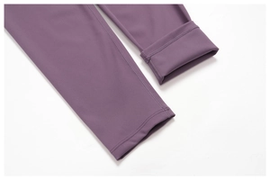 Detailed close-up of flatlock seams and reinforced hem on dark purple yoga leggings