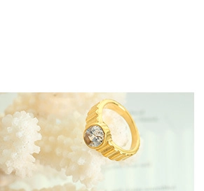 Gros plan sur une bague dorée à rainures torsadées sertie d'une pierre ronde claire