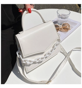 Chic white chain square bag on minimalist desk with sunglasses and lifestyle magazine