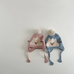 Detail of baby knitted earflap hats with chick embroidery and fluffy pom-poms