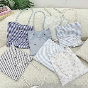 Close-up of patterned canvas tote bags with blue checks and cat prints on soft texture