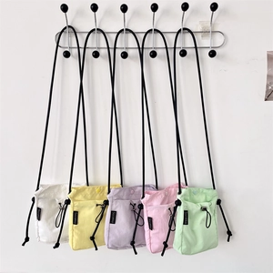 Cinque colori macaron di borse per cellulare in nylon appese su una parete bianca