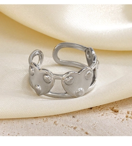Vue macro d'une bague coeur argentée ajustable avec détails perlés sur socle en pierre