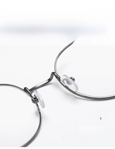 Close-up of adjustable soft silicone nose pads on black round metal eyeglass frame