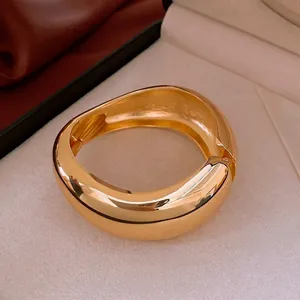 Irregular chunky gold wide bangle bracelet with organic curves on cream velvet liner