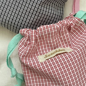 Detail of red and black checkered drawstring bags with textured woven cords