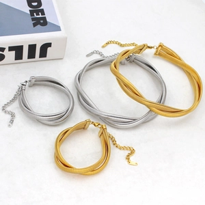 Detailed set of gold and silver double-strand twisted snake bone chain jewelry on marble