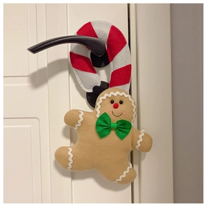 Detail of plush gingerbread man hanging on white door handle for Christmas decor