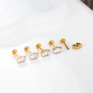 Macro detail of five gold titanium lip studs with square clear cubic zirconia crystals
