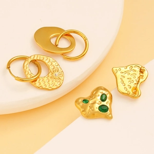 Detailed shot of gold hammered earrings with green gems and sunburst zircon accents