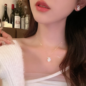 Close-up of sparkling silver bunny necklace and matching earrings set on elegant female model