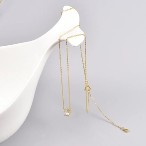 Detailed view of an 18K gold chain necklace with a clear teardrop crystal on a white stand