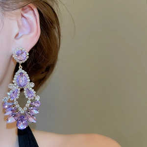 Close-up of purple teardrop tassel earrings with sparkling crystals on a female model