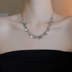 Close-up of layered silver leaf sequin necklace worn on model for a minimalist aesthetic