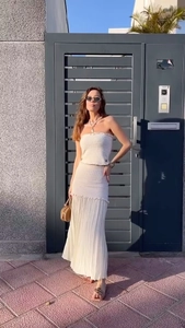 Détail du haut en tricot blanc cassé à épaules dénudées et jupe longue plissée en extérieur