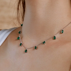 Detail of S925 silver necklace featuring emerald green teardrop-shaped zircons on model