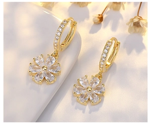 Detail of s925 silver flower earrings with gold finish and sparkling zircon stones