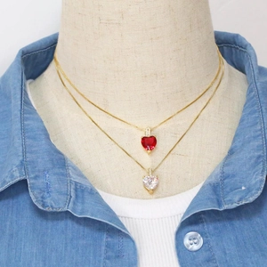Détails de pendentifs cœur en pierres précieuses rouges et blanches sur colliers dorés
