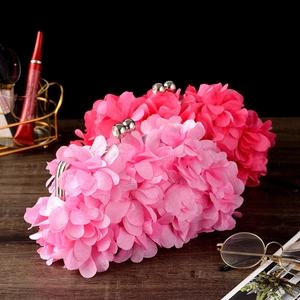 Close-up of pink and rose silk flower evening clutches with spherical metal clasps