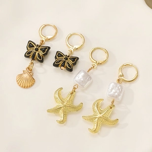 Macro view of gold seashell, starfish, and butterfly charms on 2D acrylic earrings