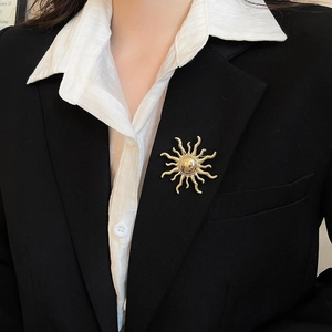 Golden sunburst brooch with polished center pinned on a black formal suit blazer