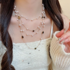 Dettaglio di una collana vintage a strati con perle e occhio di tigre indossata dal modello