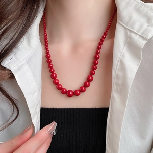 Gros plan d'un ensemble de colliers de perles rouge foncé avec perles dégradées