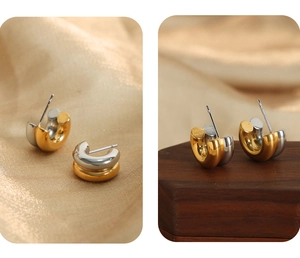 Detailed view of two-tone gold and silver U-shaped hoop earrings on silk and wood
