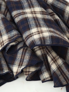 Detailed close-up of blue and brown plaid fabric texture with neat edge stitching