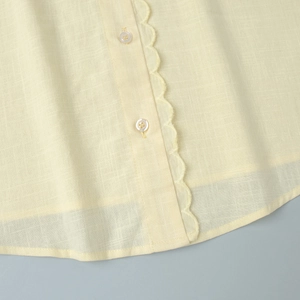 Détail de la broderie festonnée et de la texture lin du haut d'été jaune pâle à col V