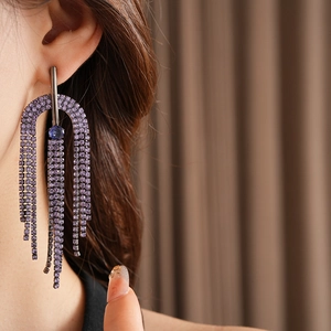 Close-up of model wearing long purple rhinestone tassel earrings with silver base