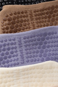Détail macro des poignées antidérapantes en silicone sur les chaussettes de yoga en coton