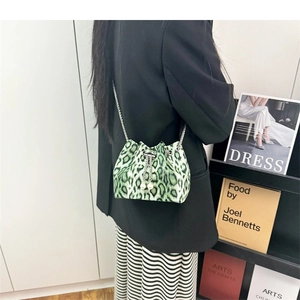 Detail view of leopard print bucket bag with silver chain and pearl drawstring on a model