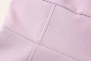 Macro detail of dusty pink dress fabric showing smooth texture and high-quality stitching