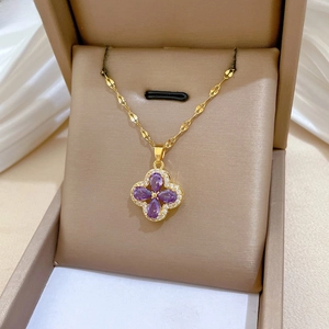 Detailed view of gold clover pendant with purple zircon stones and sparkling crystals