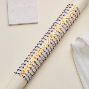 Golden Evil Eye beaded bracelet with letter charms on an elegant white display pedestal