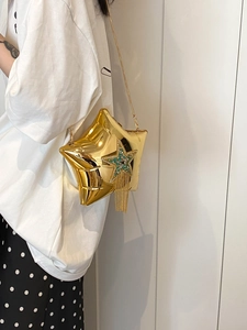 Detail of star-shaped gold bag featuring metallic fringe and green beaded star charm
