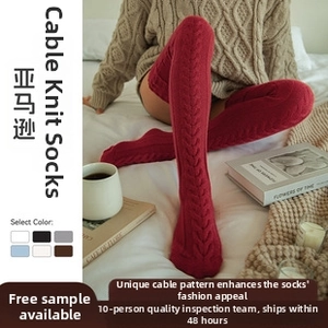 Macro shot of dark red cable-knit over-knee socks in a cozy home setting decor