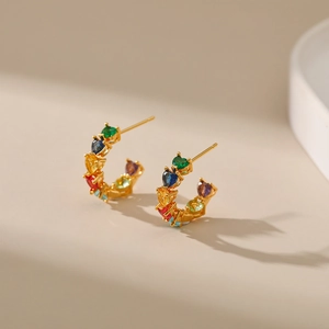 Macro shot of 18K gold plated C-shaped earrings featuring rainbow heart-cut zircons
