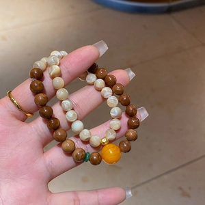 Detail of double-layer beaded bracelet featuring natural shell beads and amber center stone