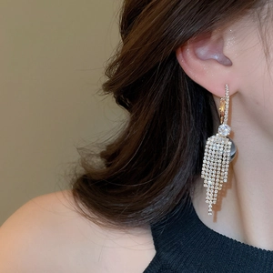 Close-up of sparkling long tassel earrings with cubic zirconia rhinestones on a model