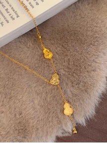 Detail of three 18k gold plated gourd pendants with fine texture on a delicate chain